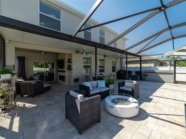 view of patio with an outdoor living space with a fire pit, a lanai, a ceiling fan, and fence