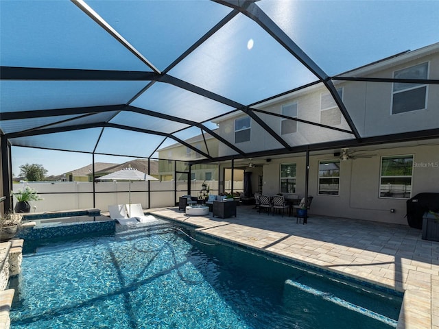 view of pool featuring outdoor lounge area, a ceiling fan, glass enclosure, a patio area, and fence