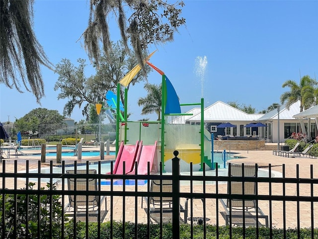 view of playground featuring fence and a community pool