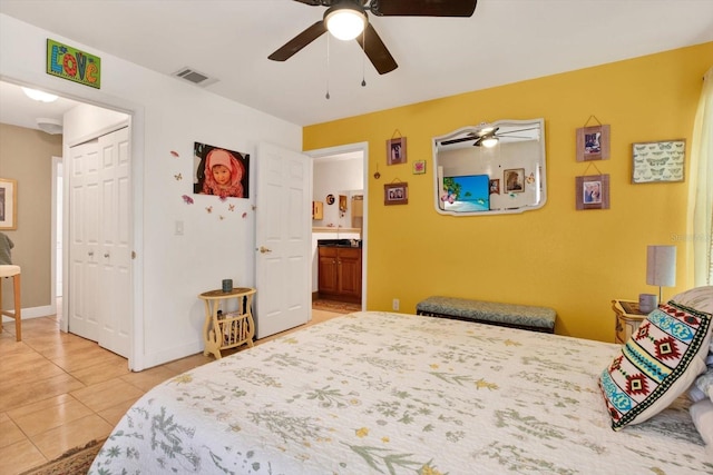 bedroom with ceiling fan, light tile patterned flooring, visible vents, a closet, and ensuite bath