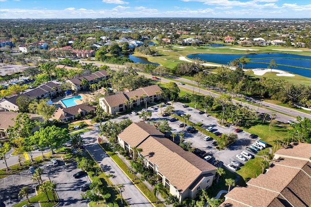 drone / aerial view featuring golf course view, a water view, and a residential view