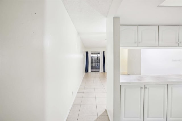 hall featuring light tile patterned flooring and baseboards