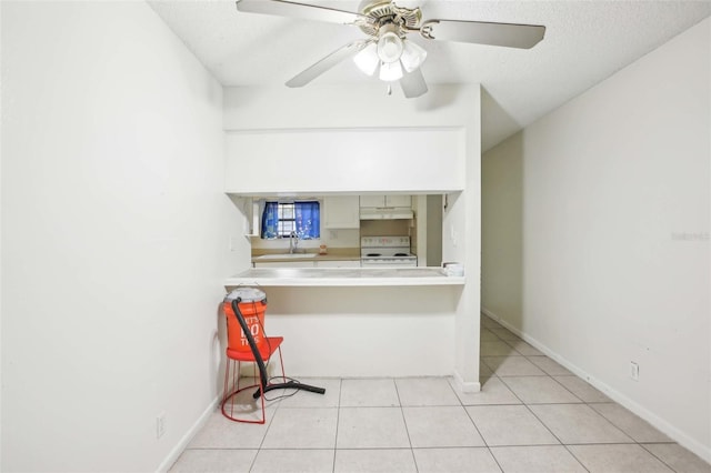 kitchen featuring light countertops, white electric range, under cabinet range hood, a sink, and light tile patterned flooring