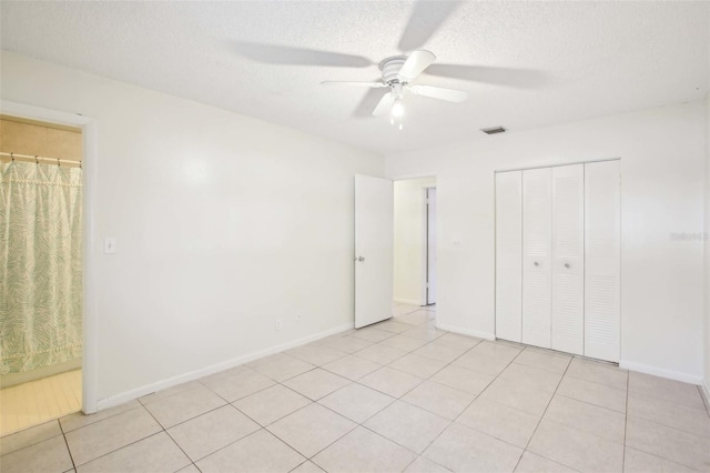 unfurnished bedroom with light tile patterned floors, a closet, visible vents, a textured ceiling, and baseboards