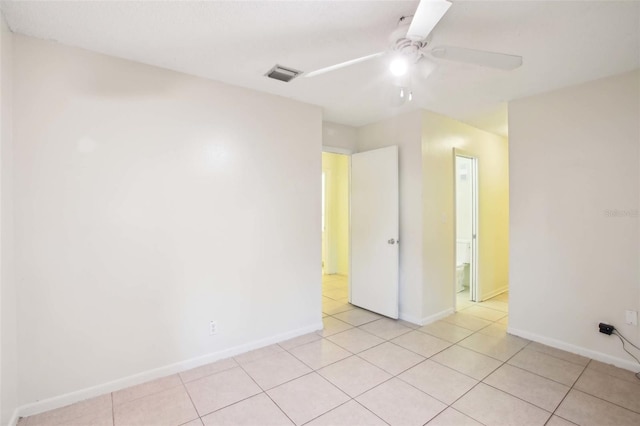 empty room with light tile patterned floors, baseboards, visible vents, and a ceiling fan