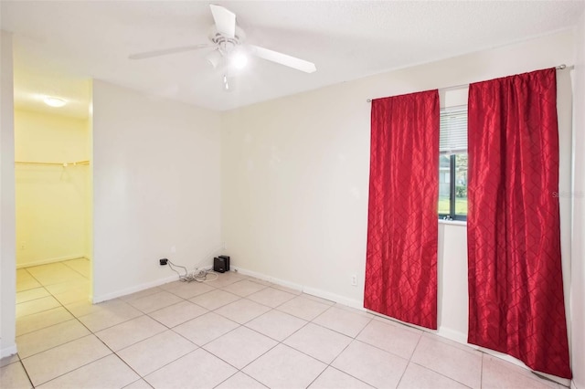 spare room featuring light tile patterned floors, ceiling fan, and baseboards