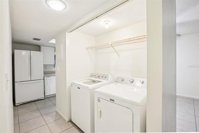 laundry room with laundry area, visible vents, light tile patterned flooring, and washing machine and clothes dryer