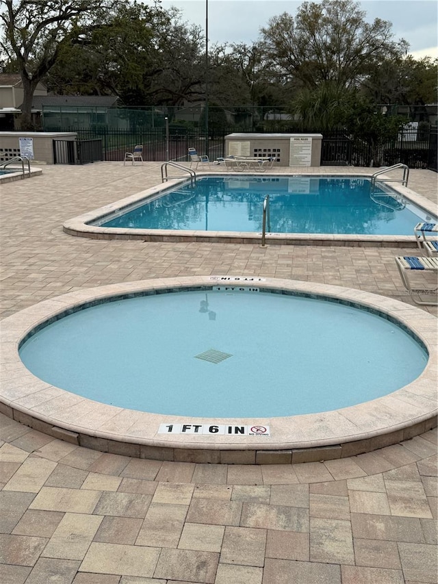 community pool featuring a patio area, fence, and a community hot tub