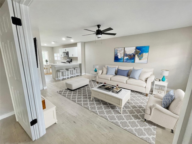 living room with a ceiling fan, light wood-type flooring, baseboards, and recessed lighting