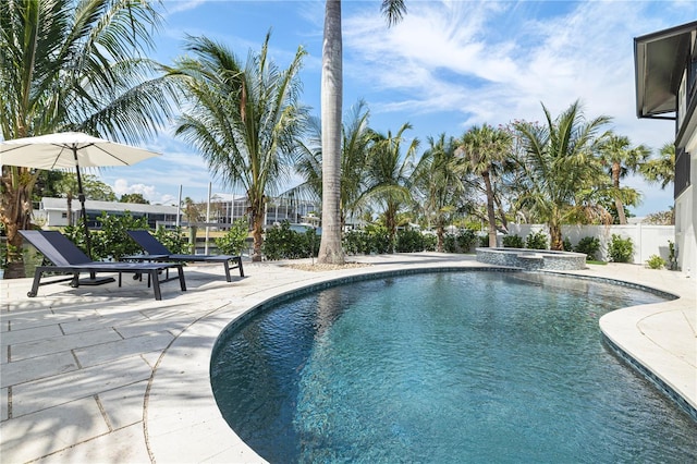 view of pool featuring a pool with connected hot tub, fence, and a patio