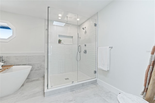 full bath with marble finish floor, a shower stall, a freestanding tub, and tile walls