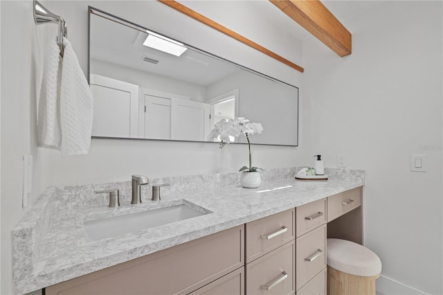 bathroom with visible vents, beamed ceiling, and vanity