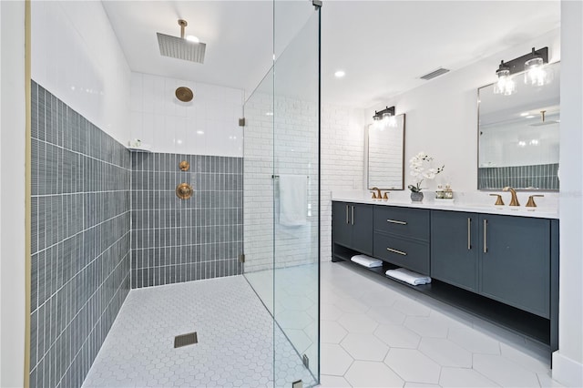 bathroom featuring double vanity, visible vents, a sink, a tile shower, and tile patterned flooring