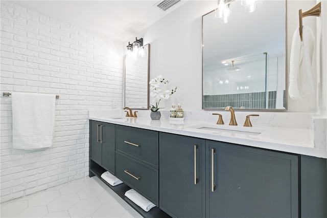 full bath featuring visible vents, a sink, brick wall, and double vanity