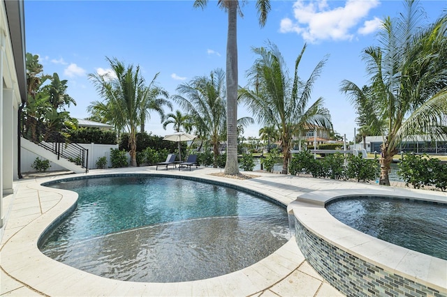 pool with an in ground hot tub, a patio, and fence