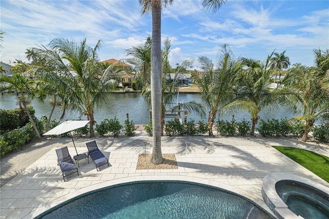 outdoor pool featuring an in ground hot tub, a patio area, and a water view