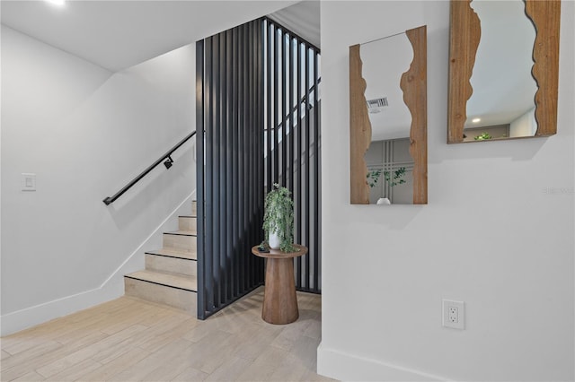 stairway with visible vents, baseboards, and wood finished floors