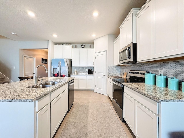 kitchen featuring stainless steel appliances, decorative backsplash, light tile patterned flooring, a sink, and white cabinetry