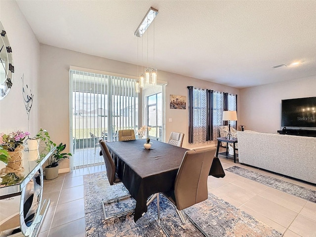 dining space featuring a healthy amount of sunlight, visible vents, a textured ceiling, and light tile patterned floors