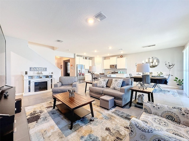 living area featuring a glass covered fireplace, visible vents, and light tile patterned floors