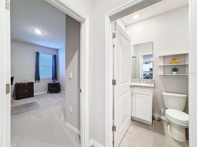 bathroom with tile patterned flooring, baseboards, vanity, and toilet