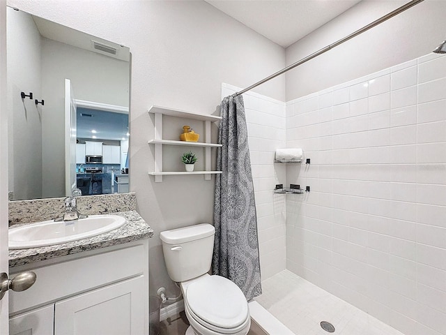 bathroom with visible vents, toilet, a tile shower, vanity, and baseboards