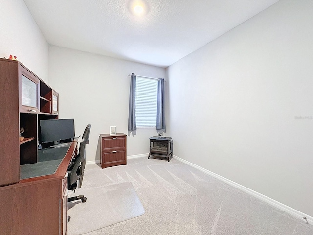 office with light carpet, a wood stove, and baseboards