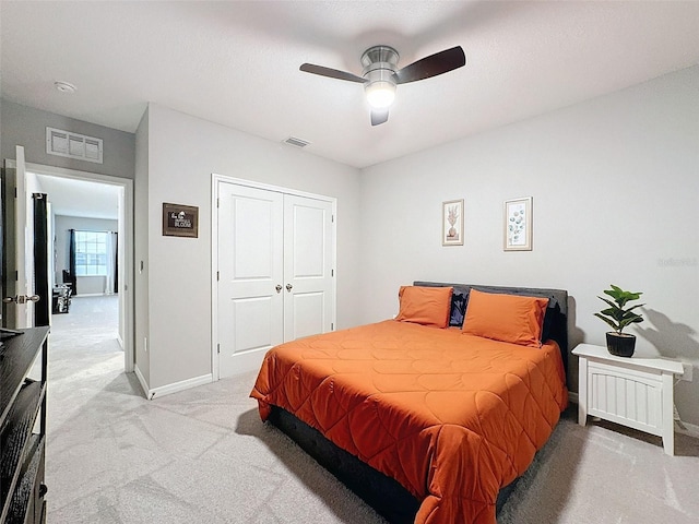 bedroom with a closet, light colored carpet, visible vents, and baseboards