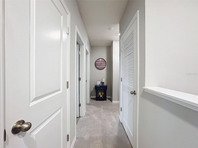 corridor with baseboards and light colored carpet