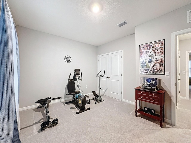 exercise room featuring carpet, baseboards, visible vents, and a textured ceiling