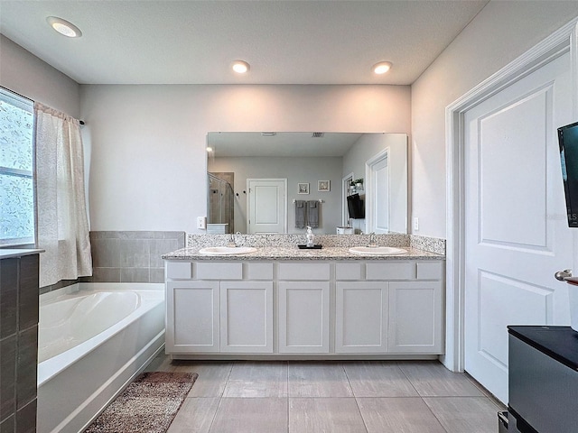 bathroom with a stall shower, a garden tub, a sink, and double vanity