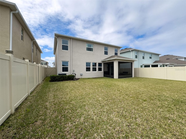 back of house with a sunroom, a fenced backyard, a lawn, and stucco siding