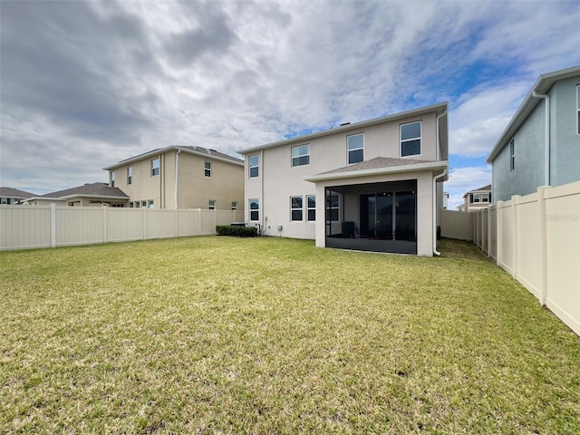 rear view of property with a sunroom, a fenced backyard, a lawn, and stucco siding