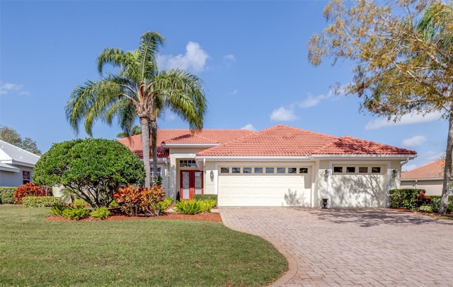 view of front of home with stucco siding, decorative driveway, a front yard, an attached garage, and a tiled roof