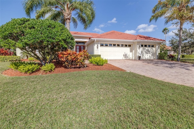 view of front of property with stucco siding, a front lawn, a tile roof, decorative driveway, and an attached garage