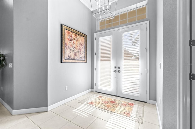 foyer entrance featuring light tile patterned floors, french doors, and baseboards