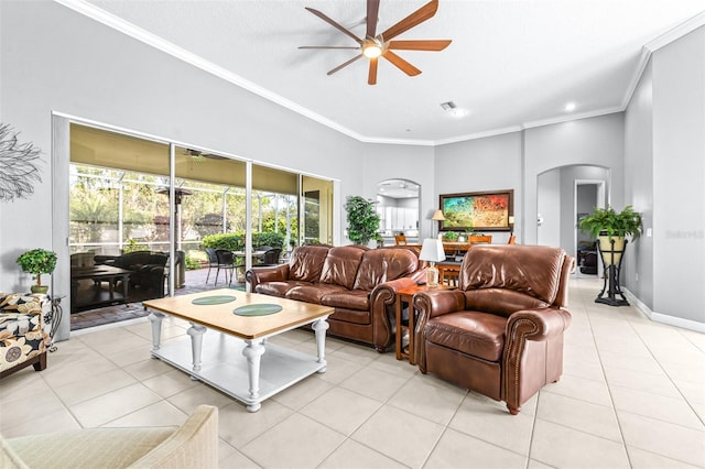 living area featuring crown molding, baseboards, ceiling fan, light tile patterned floors, and arched walkways