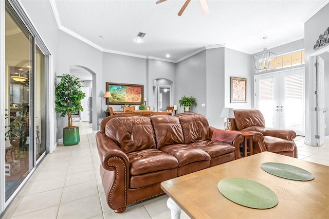 living area featuring light tile patterned floors, visible vents, arched walkways, ornamental molding, and a textured ceiling