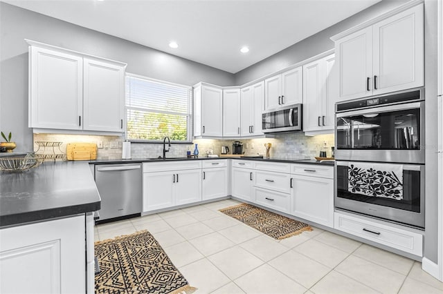 kitchen with decorative backsplash, white cabinetry, stainless steel appliances, and a sink