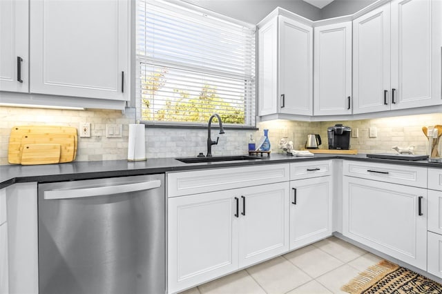 kitchen with dark countertops, light tile patterned floors, dishwasher, and a sink