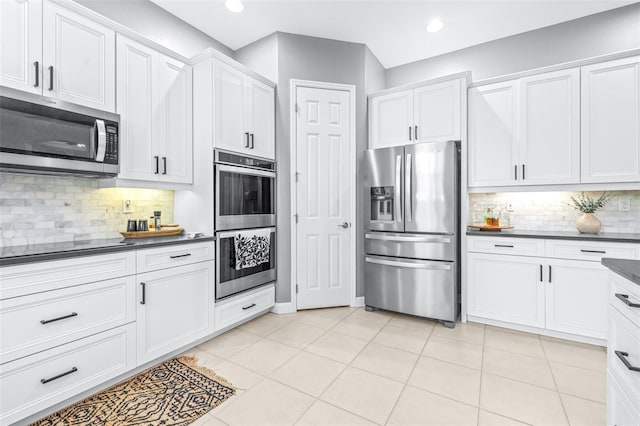 kitchen featuring light tile patterned floors, stainless steel appliances, dark countertops, and white cabinets