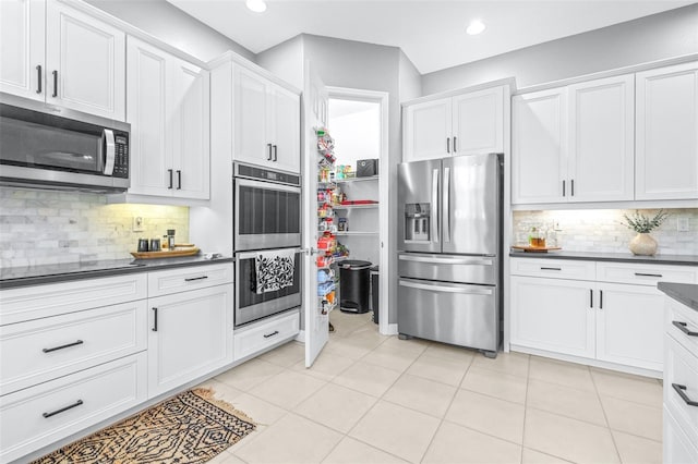 kitchen featuring dark countertops, light tile patterned floors, white cabinets, and appliances with stainless steel finishes