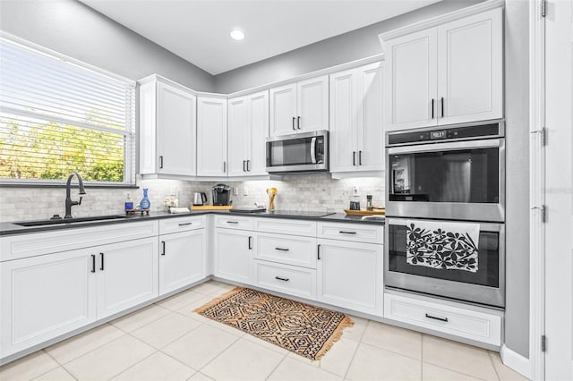 kitchen featuring dark countertops, backsplash, stainless steel appliances, and a sink