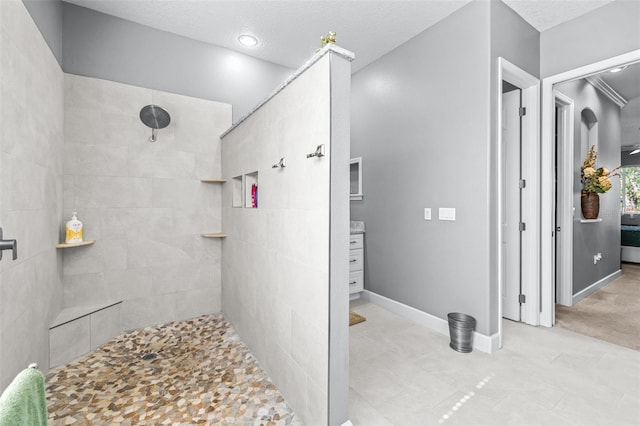 full bath with baseboards, a textured ceiling, and a tile shower