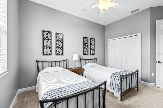 bedroom with visible vents, baseboards, light carpet, a closet, and a ceiling fan