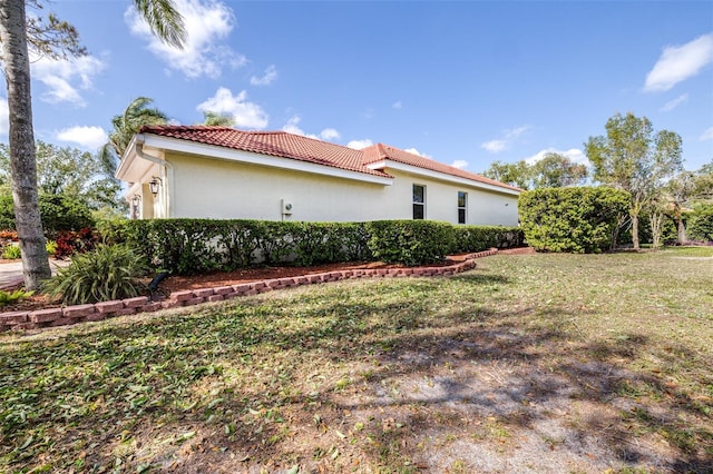 view of home's exterior with a tile roof, a yard, and stucco siding