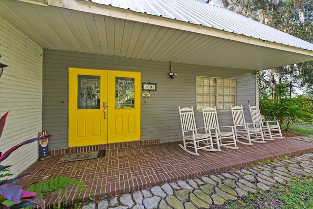 view of exterior entry with covered porch and metal roof