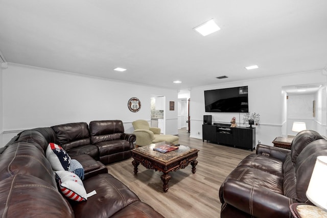 living room featuring ornamental molding, light wood finished floors, and visible vents