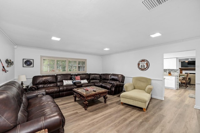 living room featuring light wood-style floors, visible vents, and crown molding