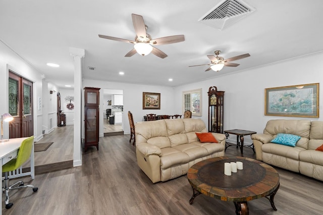 living room with recessed lighting, visible vents, wood finished floors, and ornamental molding